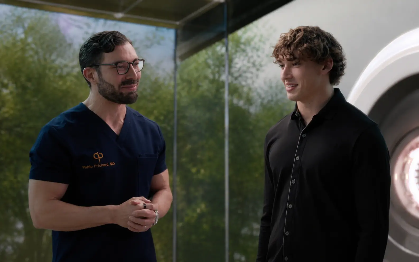 forever-young-ep-13-decathlife - Forever Young with Dr. Pablo Prichard Two men stand in a modern clinic: a fit male doctor in navy scrubs (Pablo Prichard, MD) converses with a younger decathlete Trei